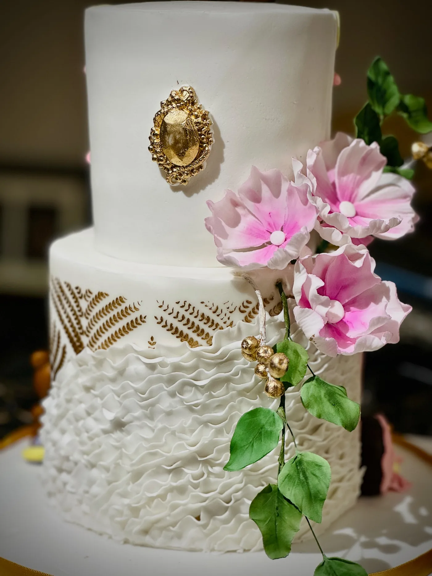 Bridal Ruffle Cake — white fondant tiers with gold brooch, stencil work and hand-crafted sugar flowers